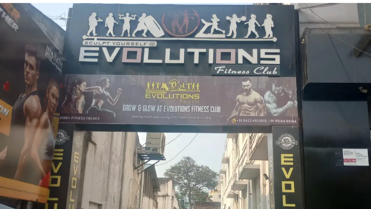 Evolutions Fitness Club gym entrance signage in Coimbatore with fitness transformation banner and contact details
