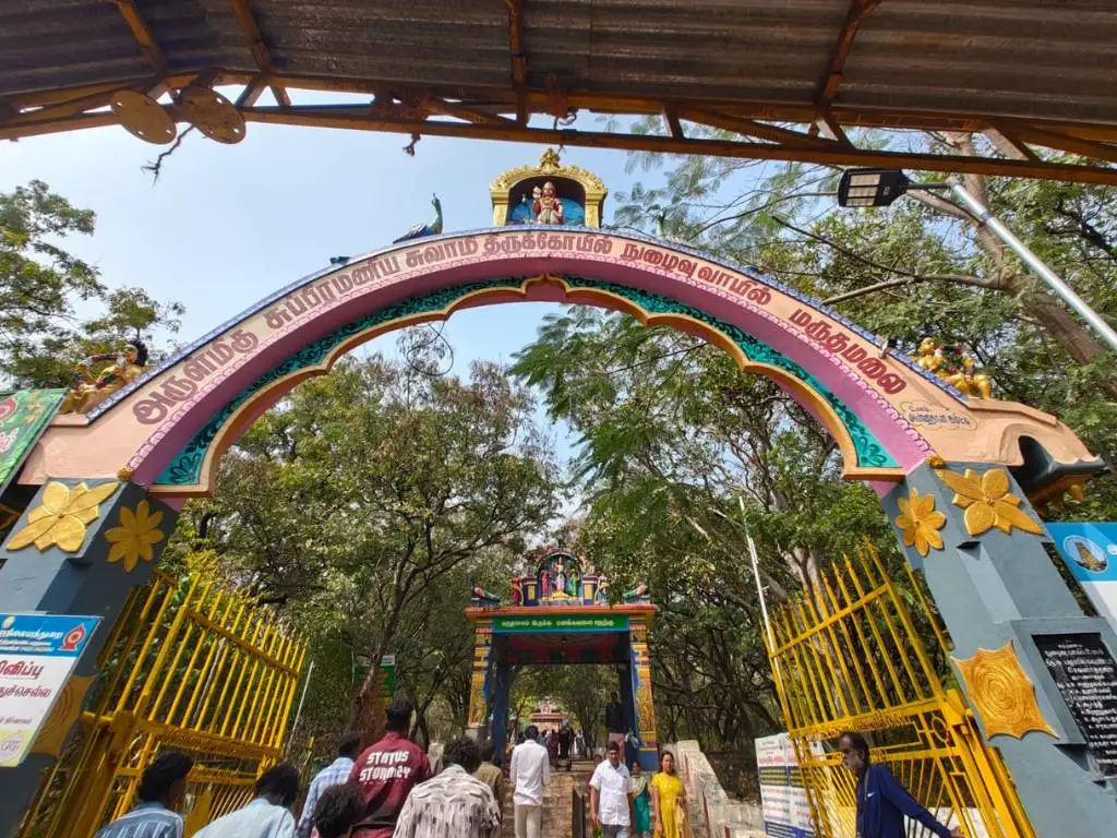 Entrance arch and steps leading to Marudhamalai Temple hilltop in Coimbatore with devotees beginning the sacred climb